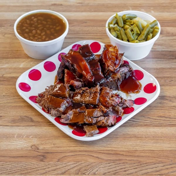 Dad's BBQ brisket and ribs with baked beans and green beans on a wooden table.