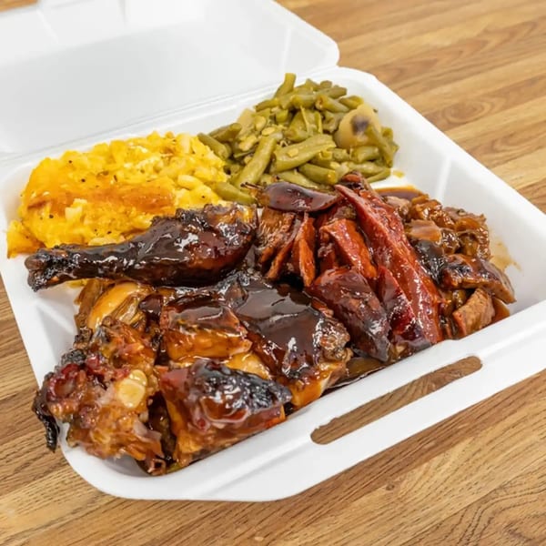 Dad's BBQ chicken, ribs, mac and cheese, and green beans in a white takeout container.