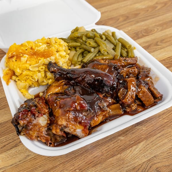 Dad's BBQ chicken, ribs, macaroni and cheese, and green beans in a takeout container.